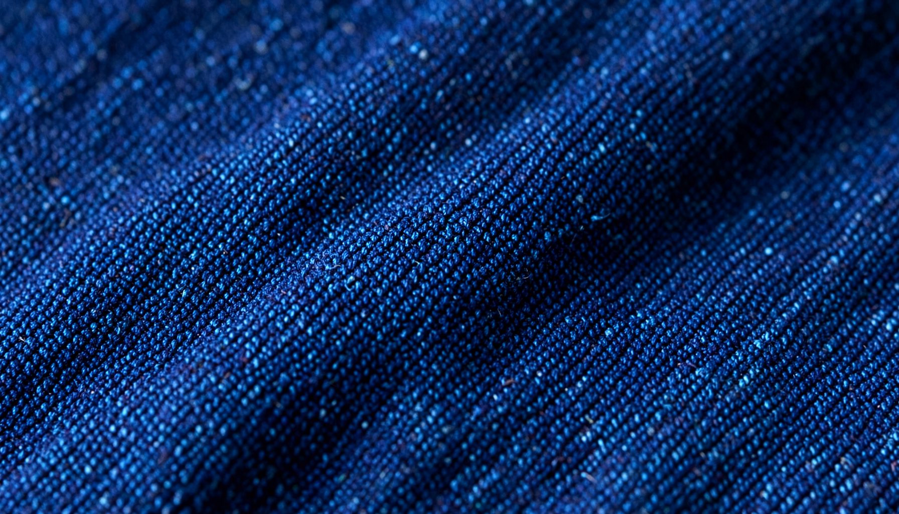 Close-up of denim fabric texture in deep indigo blue with visible weave detail