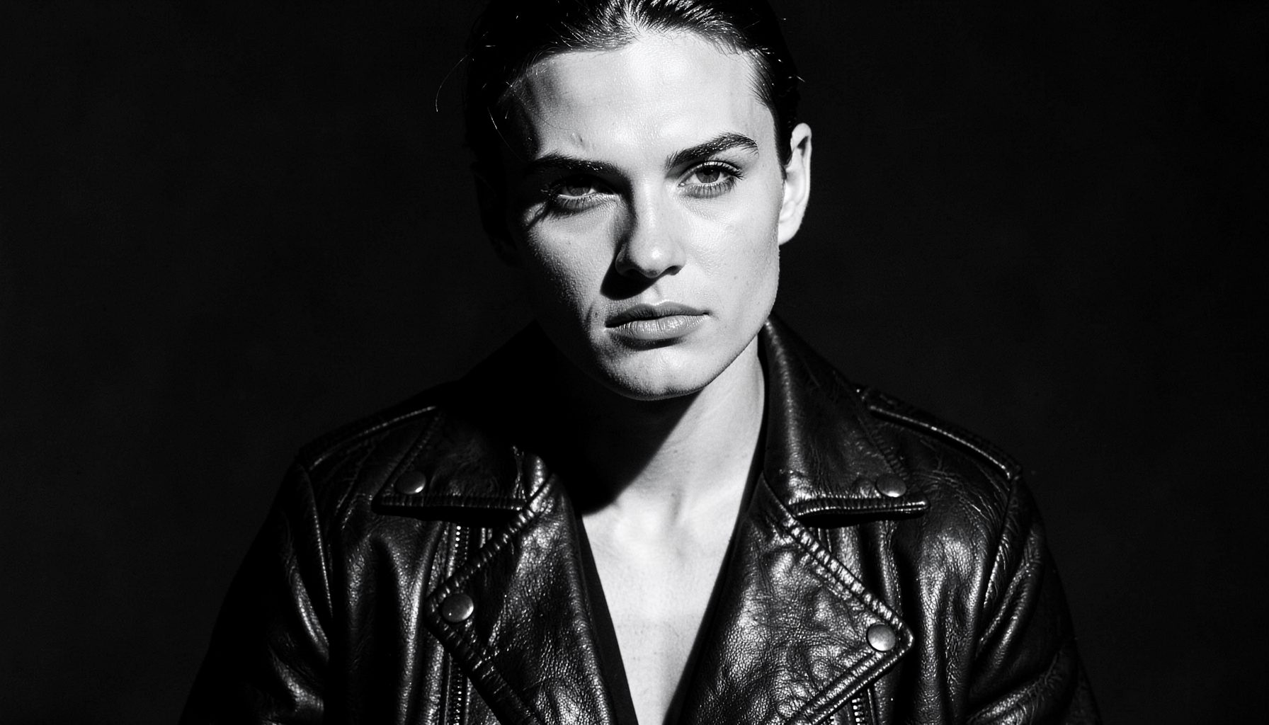 Bold black-and-white fashion portrait with dramatic shadows, leather jacket, and confident editorial styling